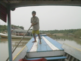 boy pushing boat down river in Cambodia