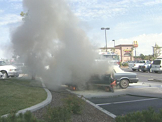 smokey car fire being put out by fire men